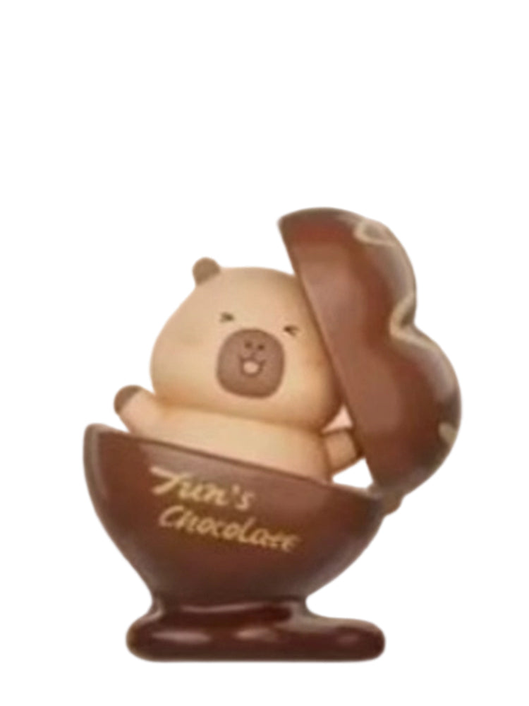 Artisan Chocolate capybara mini figure sitting in an open chocolate egg cup marked Tun's Chocolate, from the Tuntunzai Capybara Chocolate series